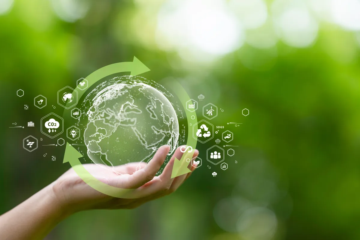 Vor grünem Hintergrund hält eine menschliche Hand eine kleine grüne Erdkugel, um die herum Recyling- und andere Kreislaufwirtschaftssymbole schweben